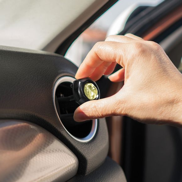 Hand placing car freshener vent clip in car air vent