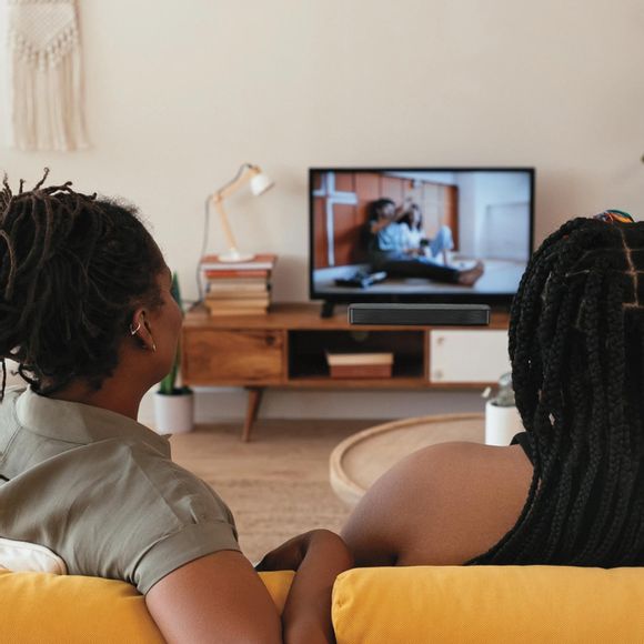 2 people watching TV with an LG Soundbar