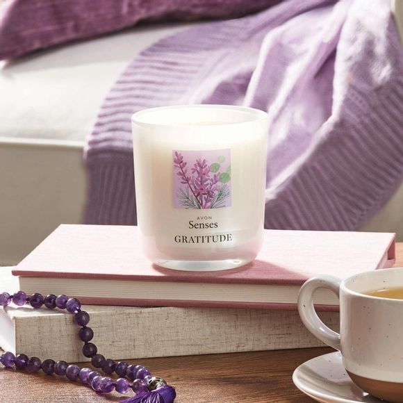 Avon Senses Gratitude fragrance diffuser on table with books, coffee and purple beeds