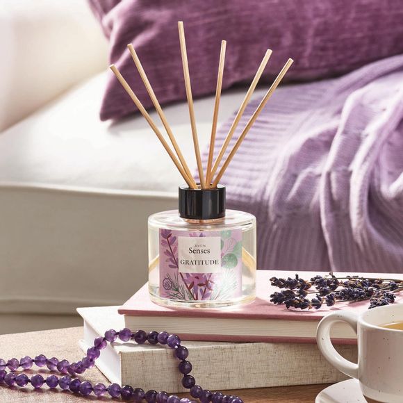 Avon Senses Gratitude fragrance diffuser on table with books, coffee and sprigs of lavender